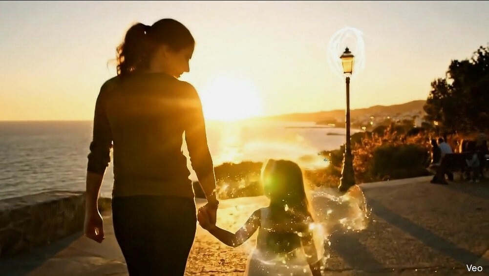 Madre caminando de la mano con su hija en un amanecer luminoso, escena final del cortometraje.